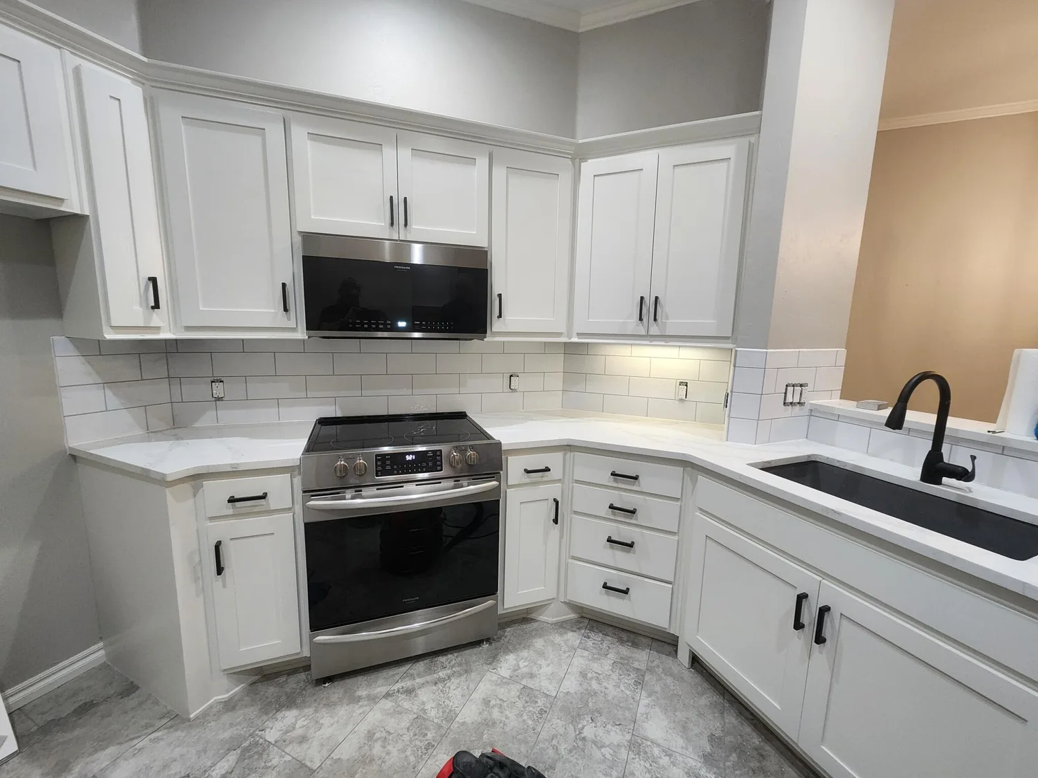 White kitchen with cabinets, tile backsplash and light countertops